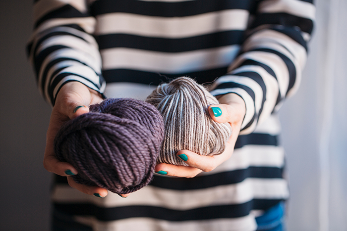 Hands of a woman holding two balls of yarn.